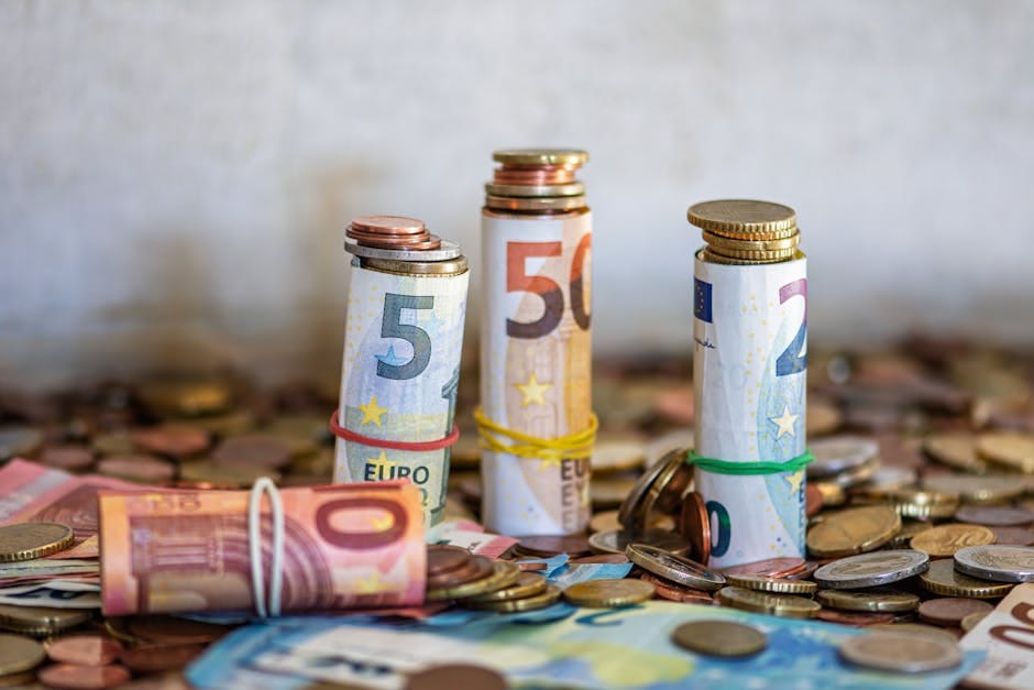 Primer plano de billetes y monedas de euro enrollados sobre una mesa, que simbolizan las finanzas y el ahorro.