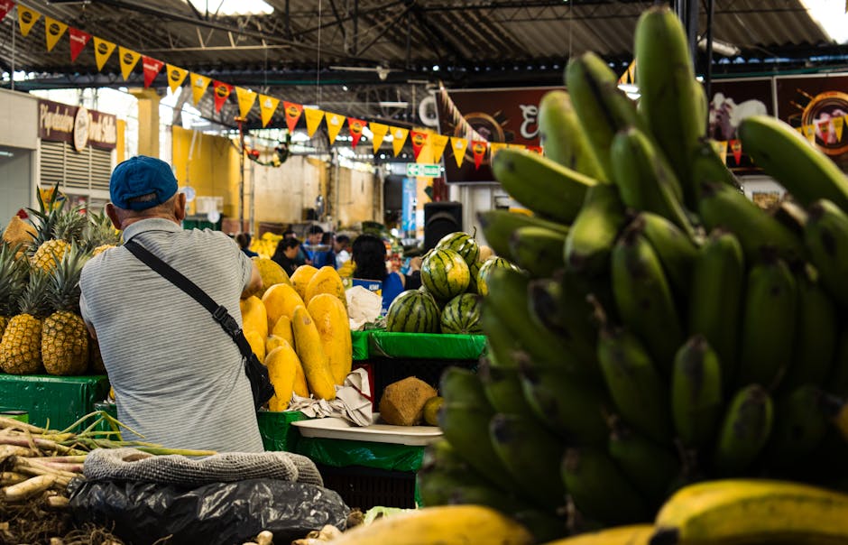 Una animada escena de mercado cubierto con una variedad de frutas frescas y un vendedor en primer plano.