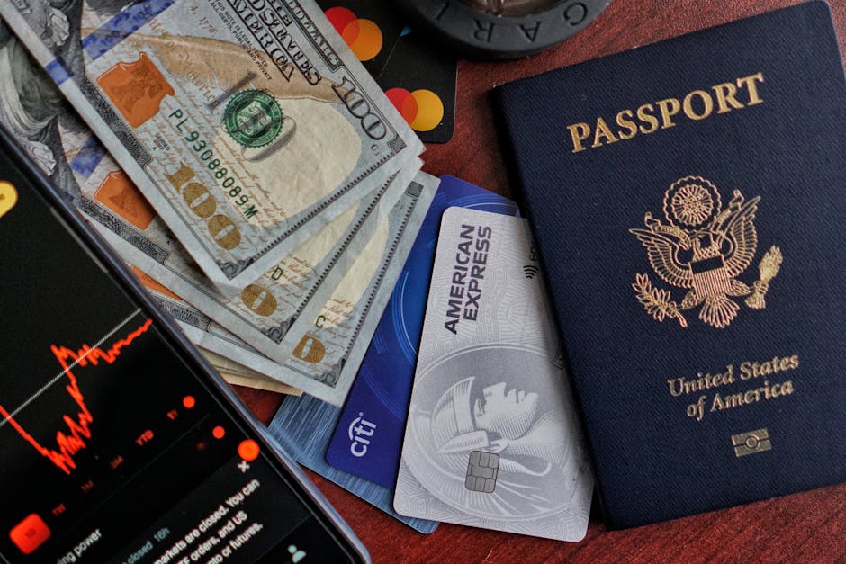 Pasaporte de Estados Unidos, efectivo, tarjetas de crédito y teléfono inteligente que muestra un gráfico del mercado de valores.