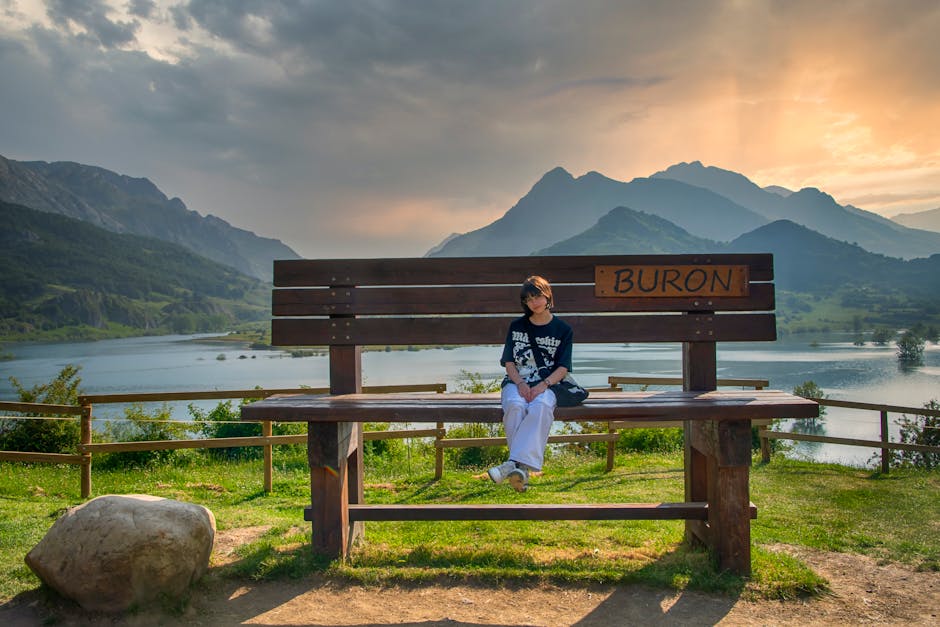 Persona sentada en un gran banco con vistas a las montañas y al lago en Burón, España.