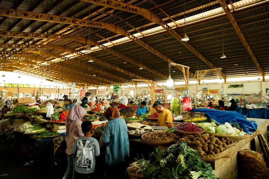 Un animado mercado cubierto con una gran variedad de frutas y verduras frescas expuestas bajo un techo de madera.