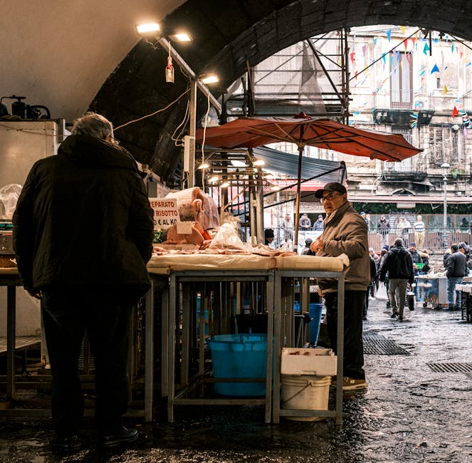 Descubre el ambiente vibrante de un bullicioso mercado de pescado en Catania, Sicilia, donde podrás admirar a los vendedores locales y sus productos frescos.