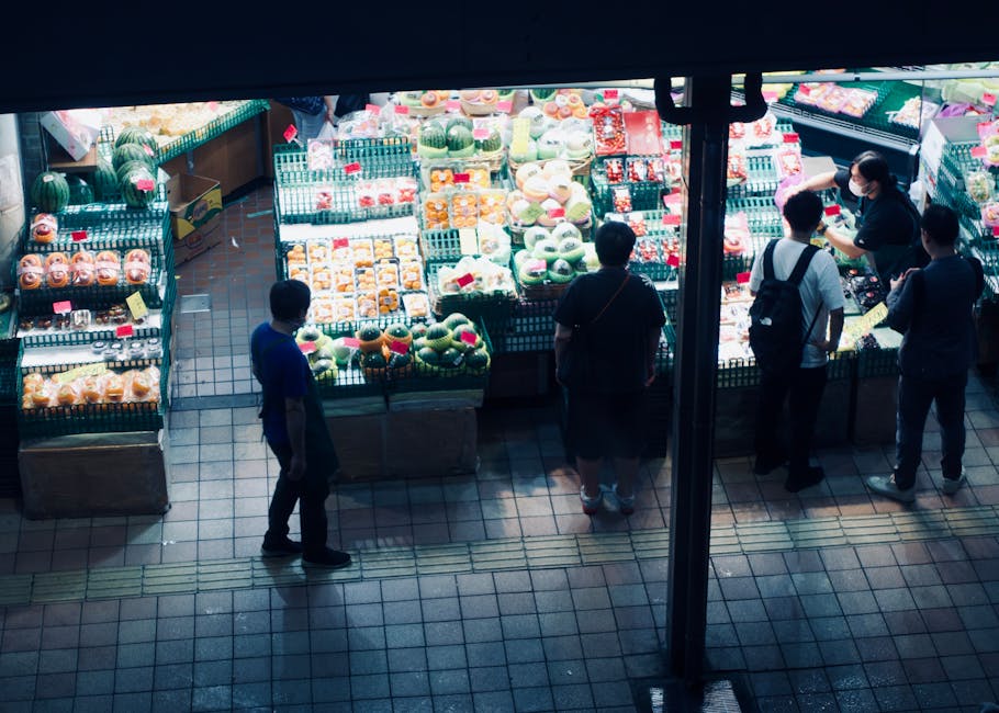 Vibrante escena de mercado nocturno que muestra una variedad de frutas frescas y clientes curioseando.