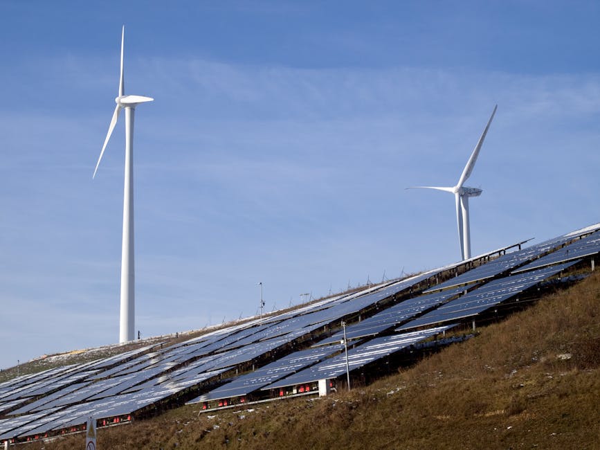Turbinas eólicas y paneles solares en una ladera aprovechando la energía renovable bajo un cielo despejado.