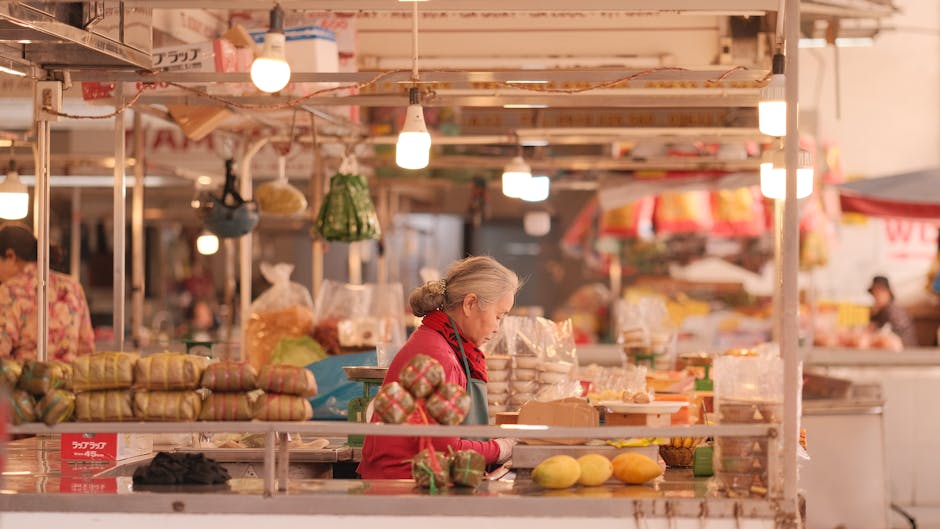 Escena de mercado bulliciosa con diversos productos alimenticios y un vendedor anciano sumido en sus pensamientos.