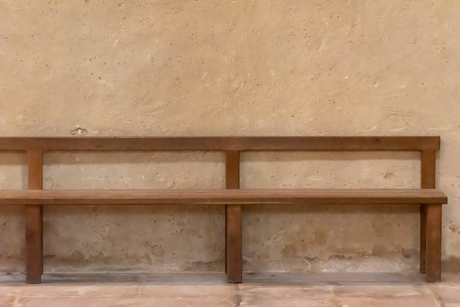 Banco de madera sencillo colocado contra una pared de piedra rústica, mostrando un diseño minimalista.