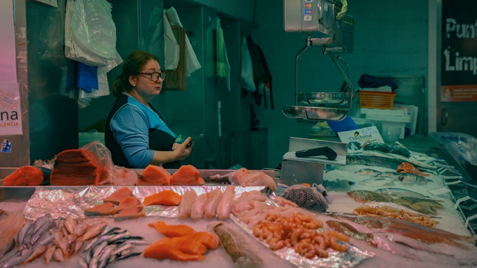 Vendedora en el mercado de Valencia mostrando una variedad de pescado y mariscos frescos.