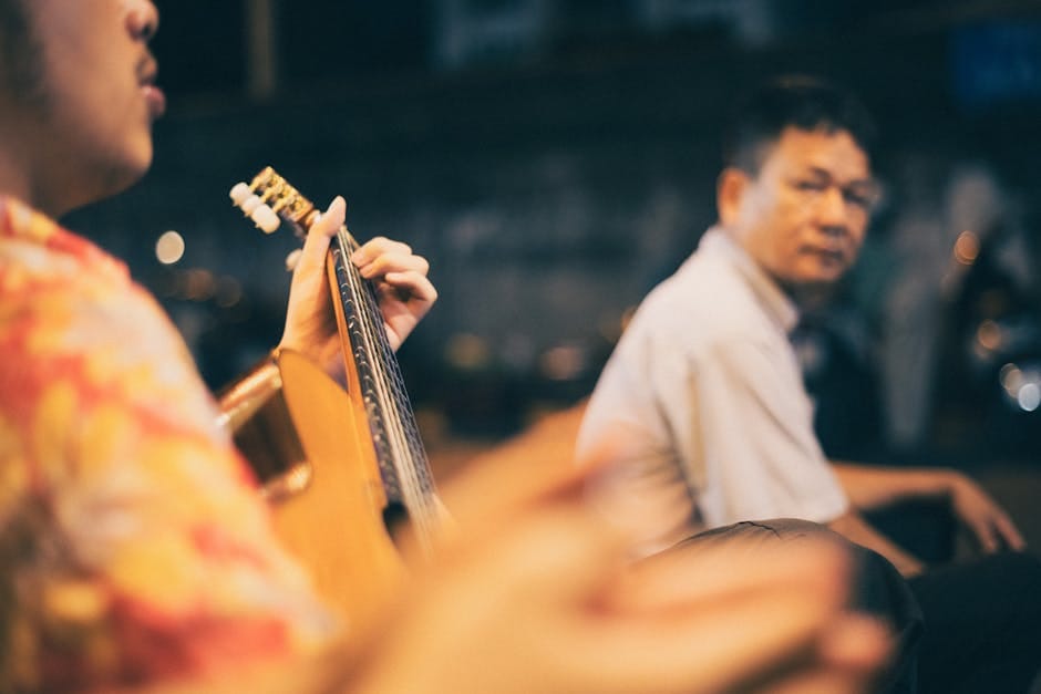 Músico tocando la guitarra por la noche en Hanoi, capturando la vida urbana en Vietnam.