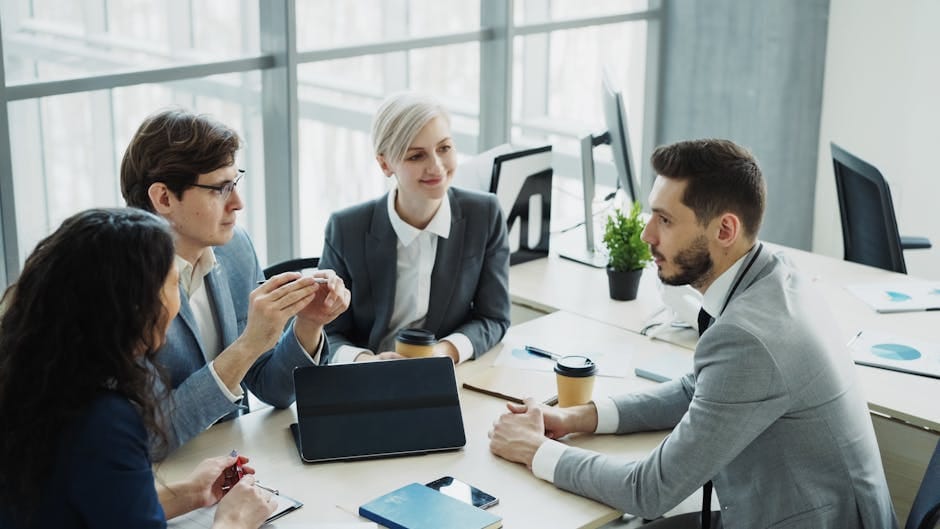 Grupo de profesionales manteniendo una conversación en un entorno de oficina moderno con luz natural.