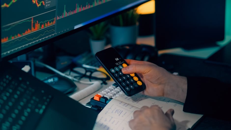 Análisis de negocios con calculadora y monitor de computadora que muestra gráficos y tablas financieras.