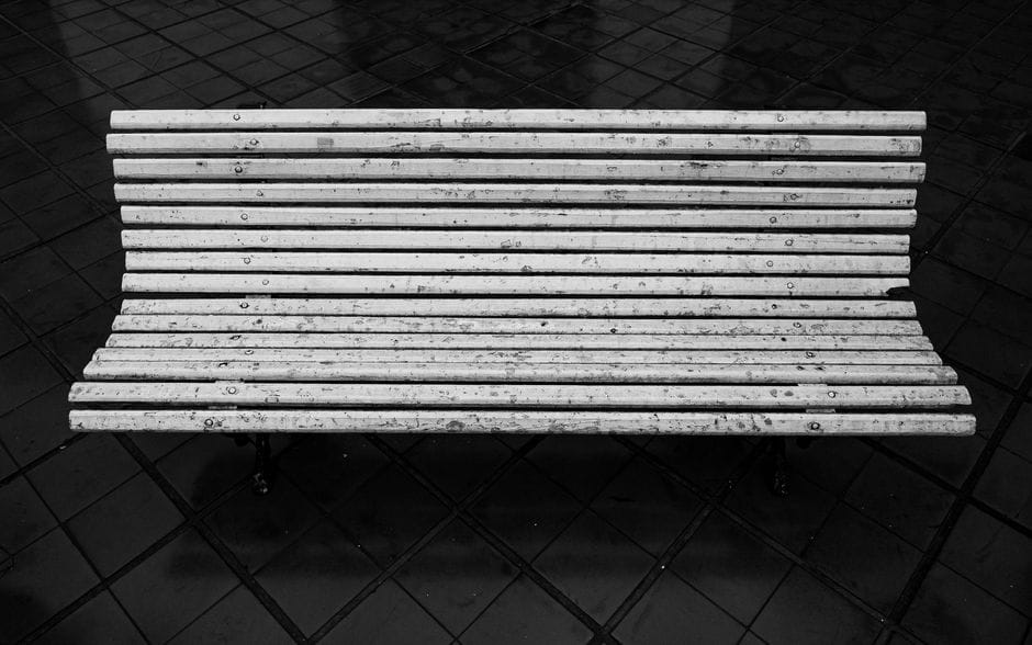 Fotografía minimalista en blanco y negro de un banco de madera sobre un piso de baldosas en Buenos Aires.