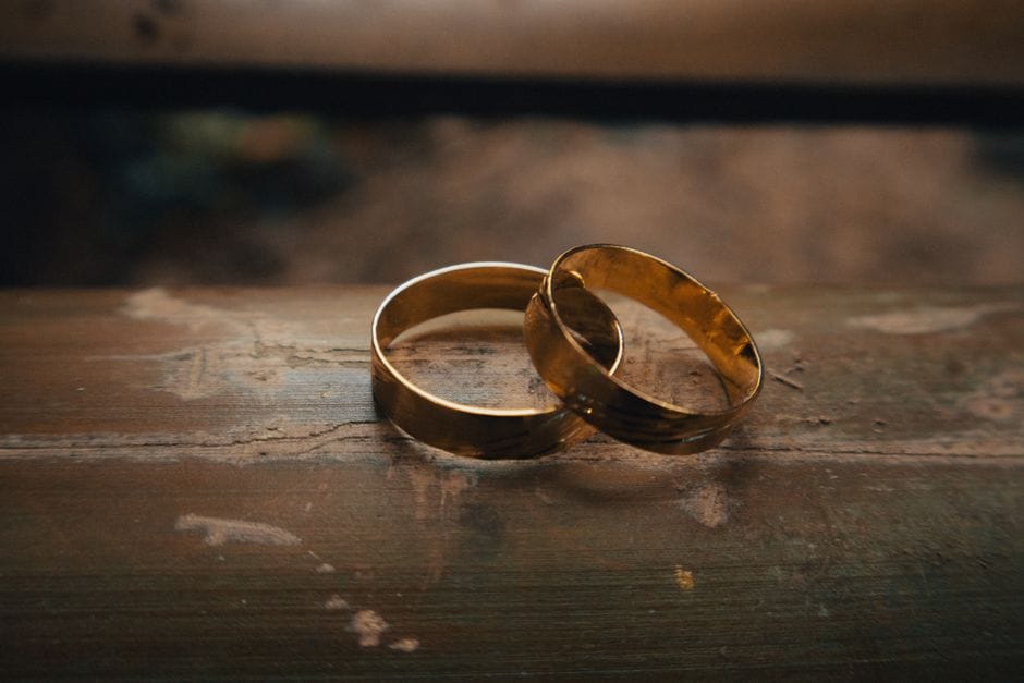 Preciosos anillos de boda de oro colocados elegantemente sobre una superficie de madera rústica.