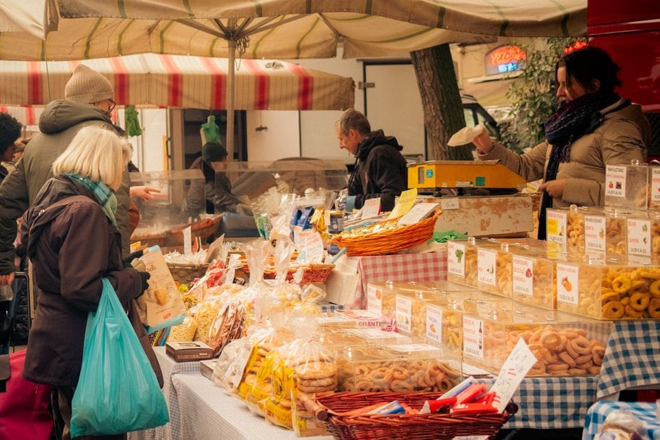 Descubre un bullicioso mercado de agricultores en Milán, con puestos llenos de vida que ofrecen pasteles y productos locales.