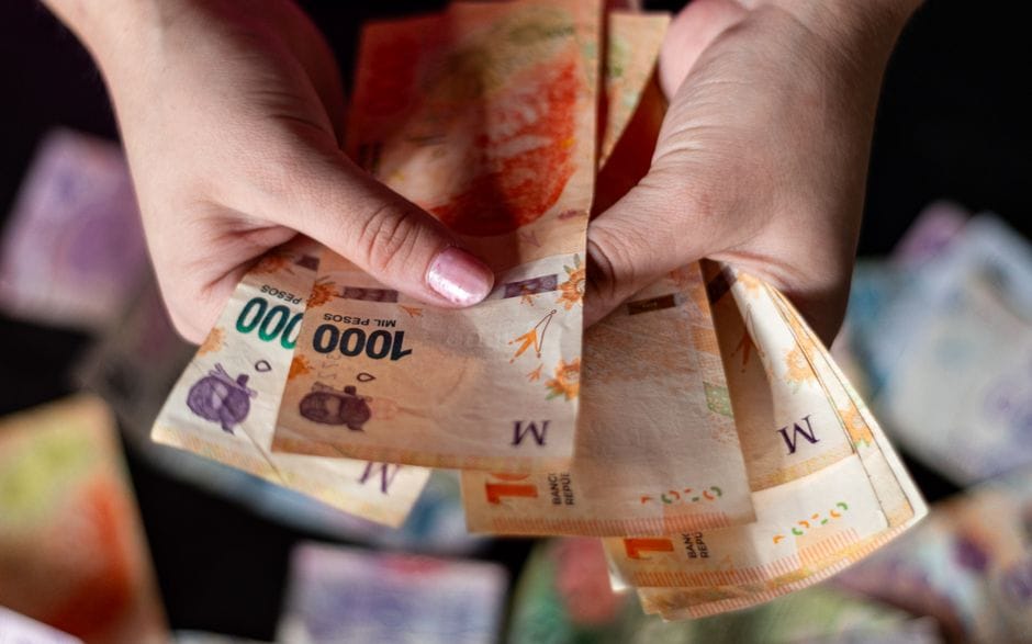 Vista detallada de manos sosteniendo billetes de pesos argentinos, simbolizando conceptos financieros.