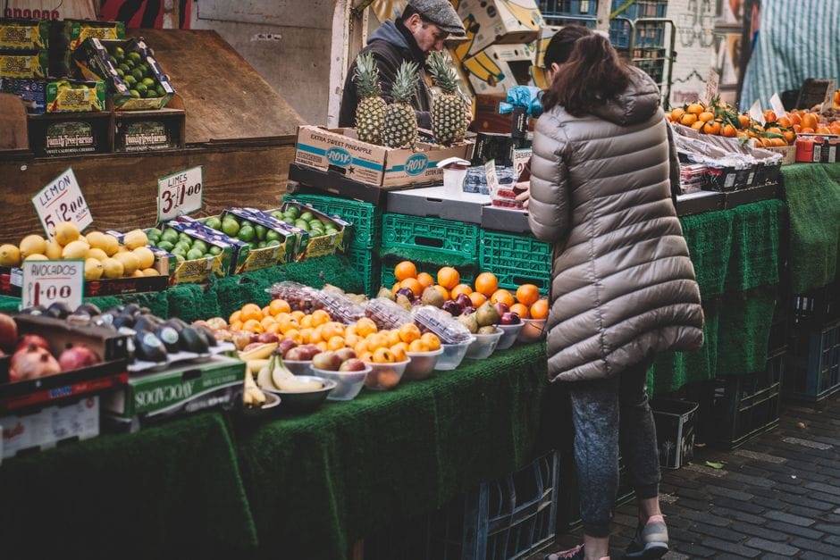Mujer De Pie Delante De Una Variedad De Frutas Mostradas