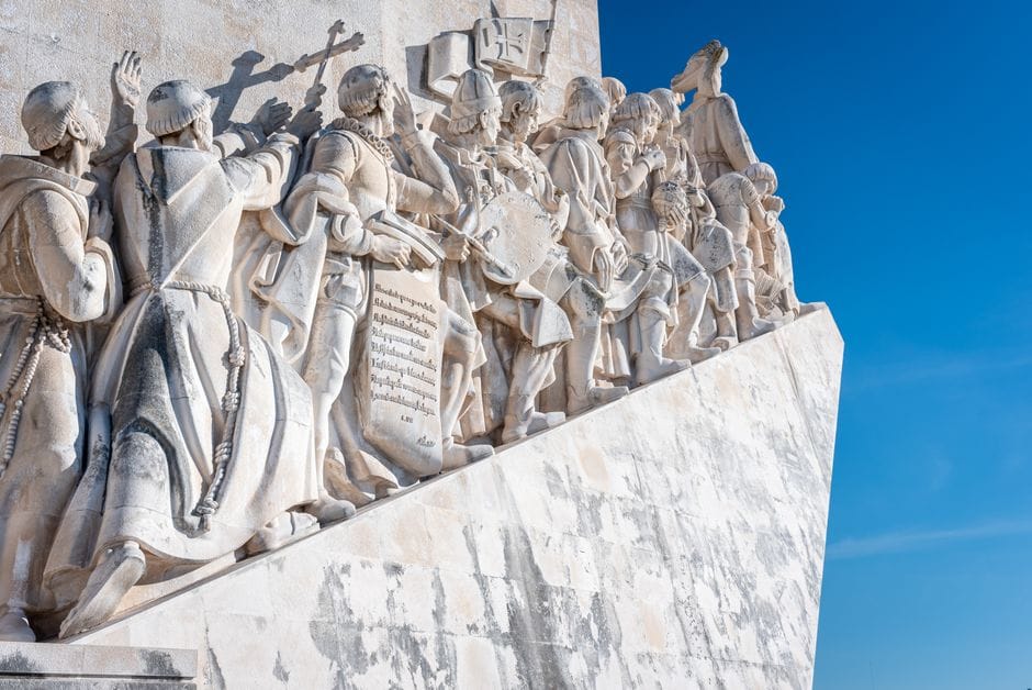 Esculturas de piedra de exploradores en el Monumento a los Descubrimientos en Lisboa contra un cielo azul.