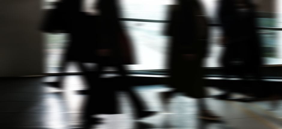 Movimiento borroso abstracto de personas caminando en interiores, que representa la vida urbana y rutinas ocupadas.