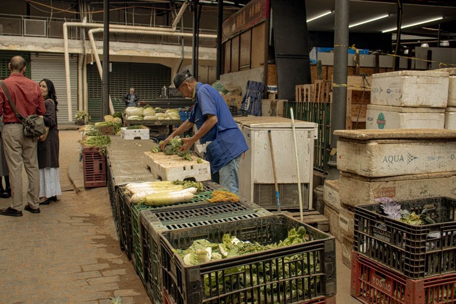 Un animado mercado cubierto con gente y verduras frescas en exhibición.