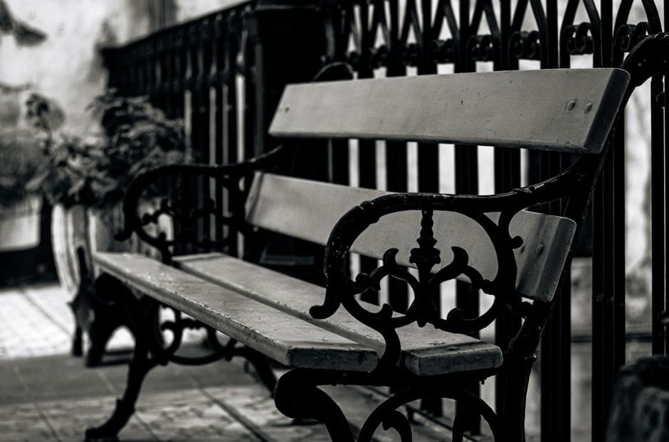 Una fotografía en blanco y negro de un banco de hierro antiguo en un balcón de Buenos Aires, Argentina.