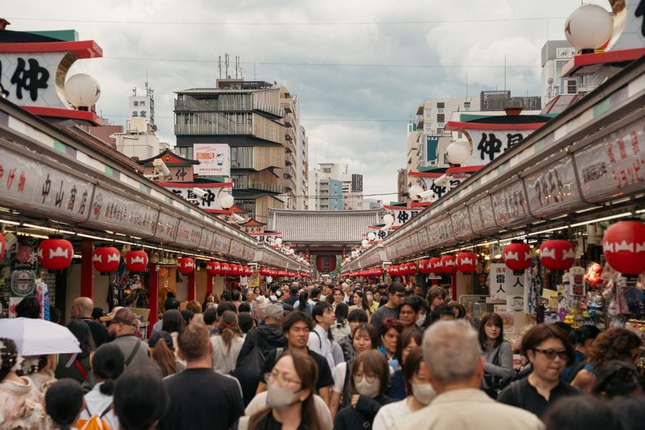 Animado mercado callejero en Asakusa, Tokio, con farolillos rojos y una multitud bulliciosa.