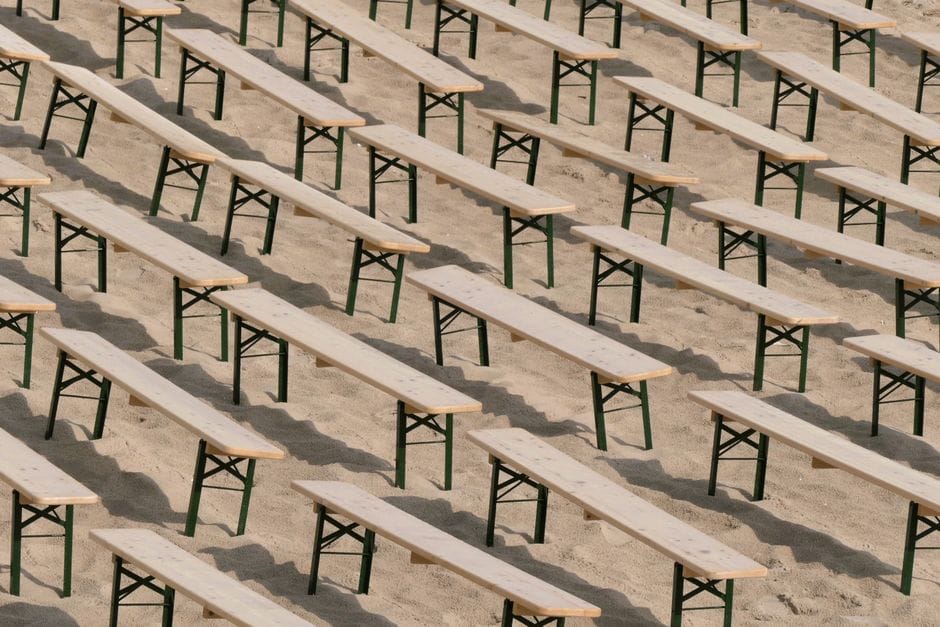 Filas de bancos de madera ordenadamente dispuestas en una playa de arena en Heringsdorf, Alemania.
