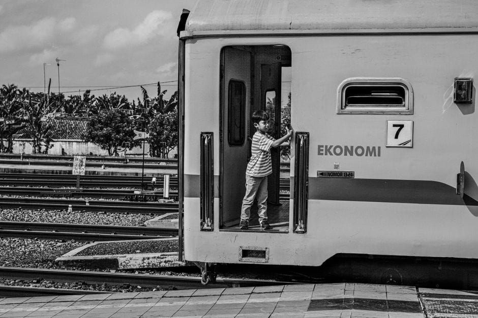 Un niño de pie en la puerta de un tren indonesio en una estación de Yakarta.