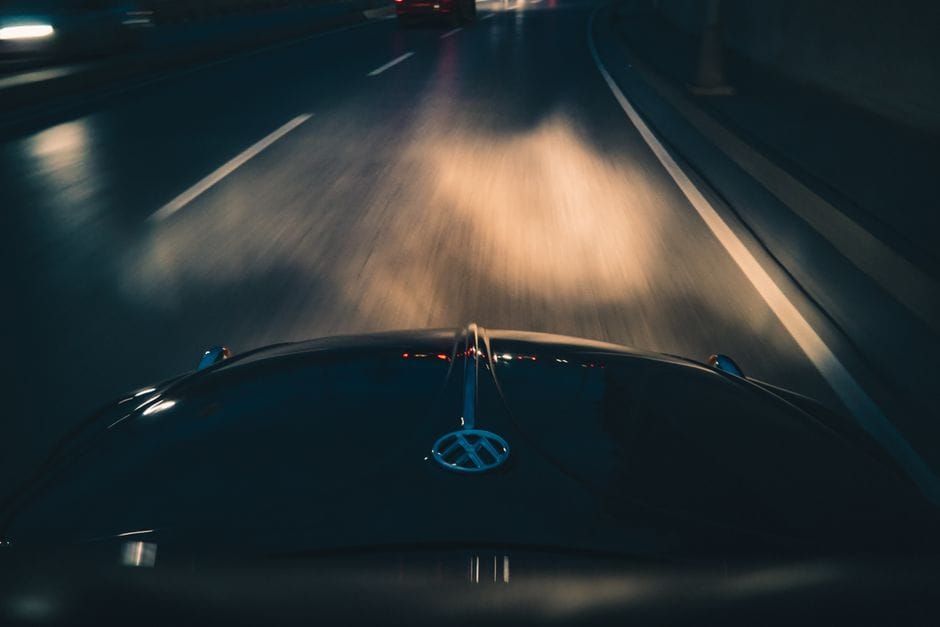 Imagen dinámica de conducción nocturna que muestra desenfoque de movimiento mientras un coche viaja por una autopista. Perfecta para temas de transporte.