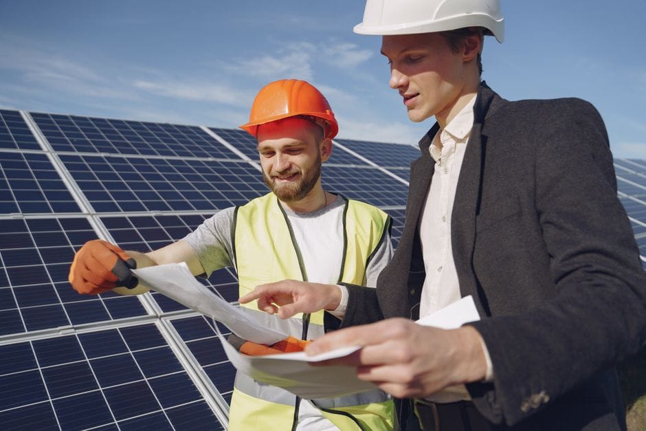 Dos ingenieros revisando planes para la instalación de paneles solares, representando el trabajo en equipo en energía renovable.