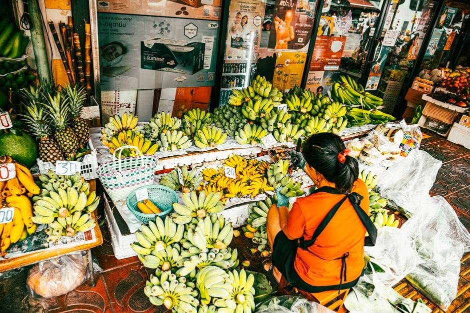Vendedor ambulante que ofrece plátanos surtidos en un vibrante mercado al aire libre en Bangkok, Tailandia.