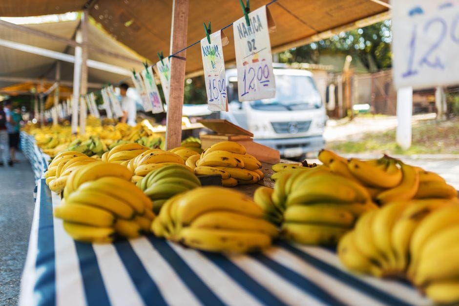 Puesto de mercado al aire libre colorido con plátanos frescos en exposición, que ofrece una animada experiencia de compra.