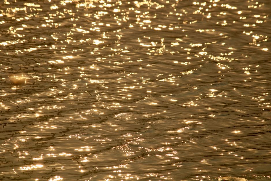 Los reflejos dorados brillantes crean un efecto calmante sobre el agua ondulante.