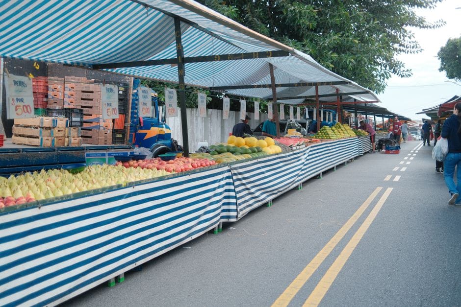 Explore un animado mercado de frutas al aire libre con coloridos puestos de productos que bordean la calle.