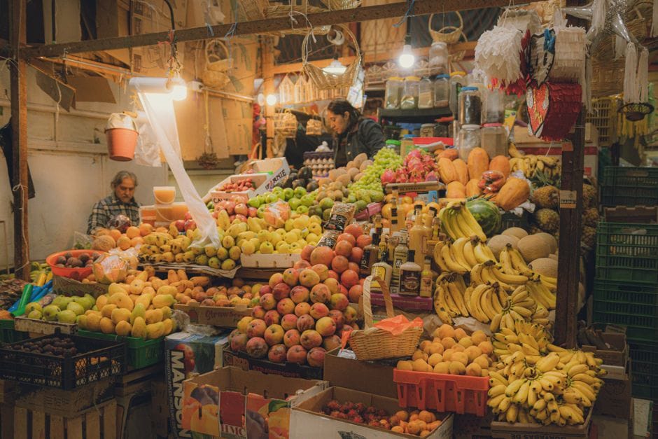 Puesto de frutas colorido en Guanajuato, México, que muestra una variedad de productos frescos en un mercado bullicioso.