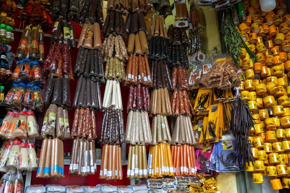 Puesto de mercado vibrante con una variedad de especias, velas y productos envasados en exhibición.