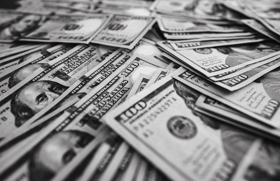 Imagen monocromática de billetes de cien dólares estadounidenses dispersos que representan riqueza y prosperidad.