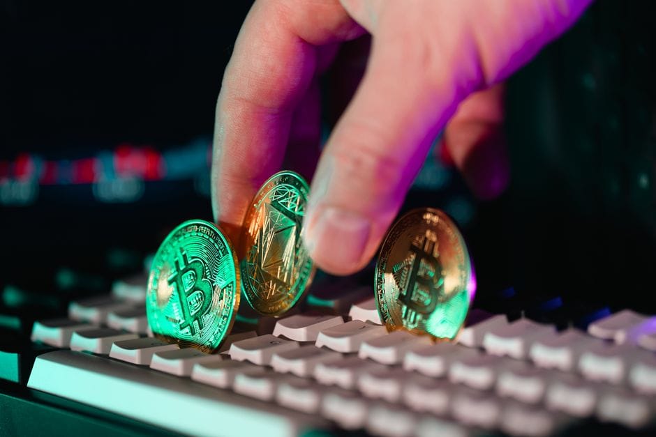 Primer plano de monedas de criptomonedas en un teclado con una mano, que simboliza la moneda digital y la tecnología financiera.