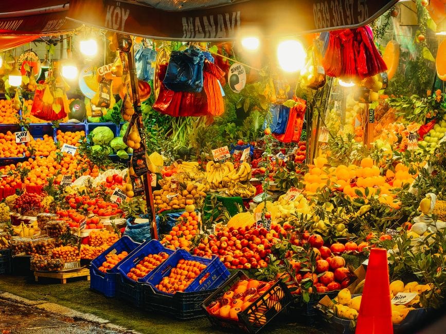 Frutas y verduras coloridas bellamente exhibidas en un concurrido puesto del mercado nocturno de Estambul.