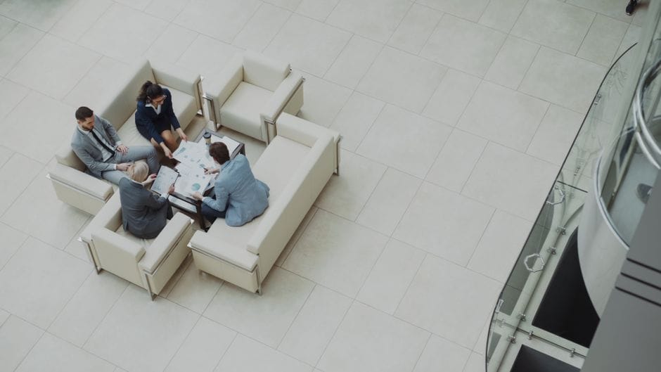 Vista aérea de un equipo de negocios discutiendo documentos en un entorno de oficina moderno.