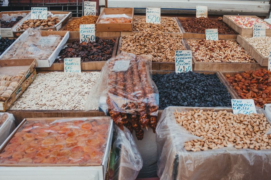 Exposición de frutos secos y nueces variadas en un mercado al aire libre en un entorno vibrante y colorido.