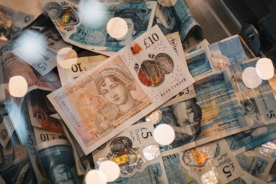 Una vista detallada de billetes y monedas de libras esterlinas británicas de 5 y 10 libras esterlinas, con cálidos efectos bokeh.