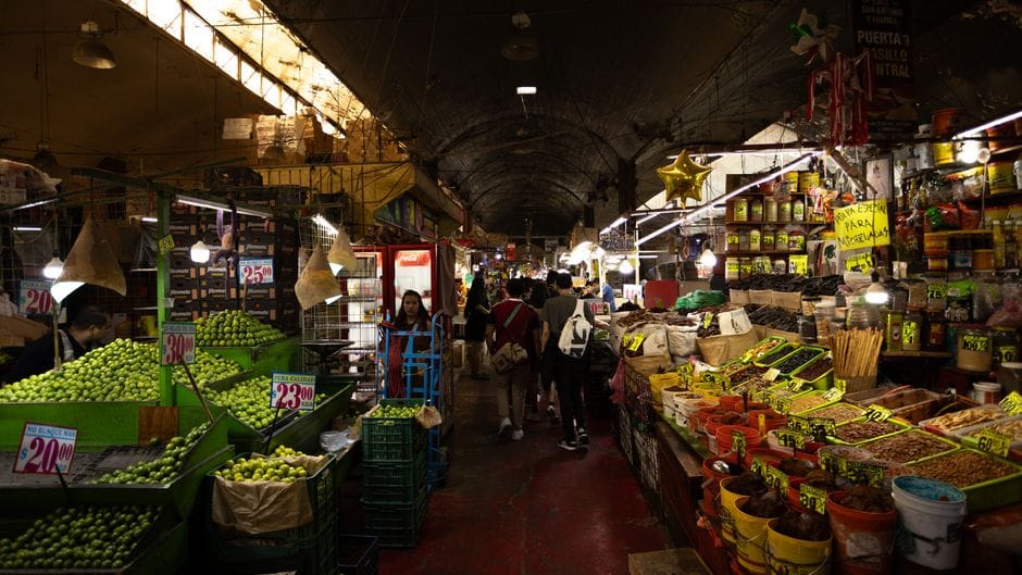 Mercado colorido y bullicioso en la Ciudad de México que exhibe productos frescos y artículos locales.