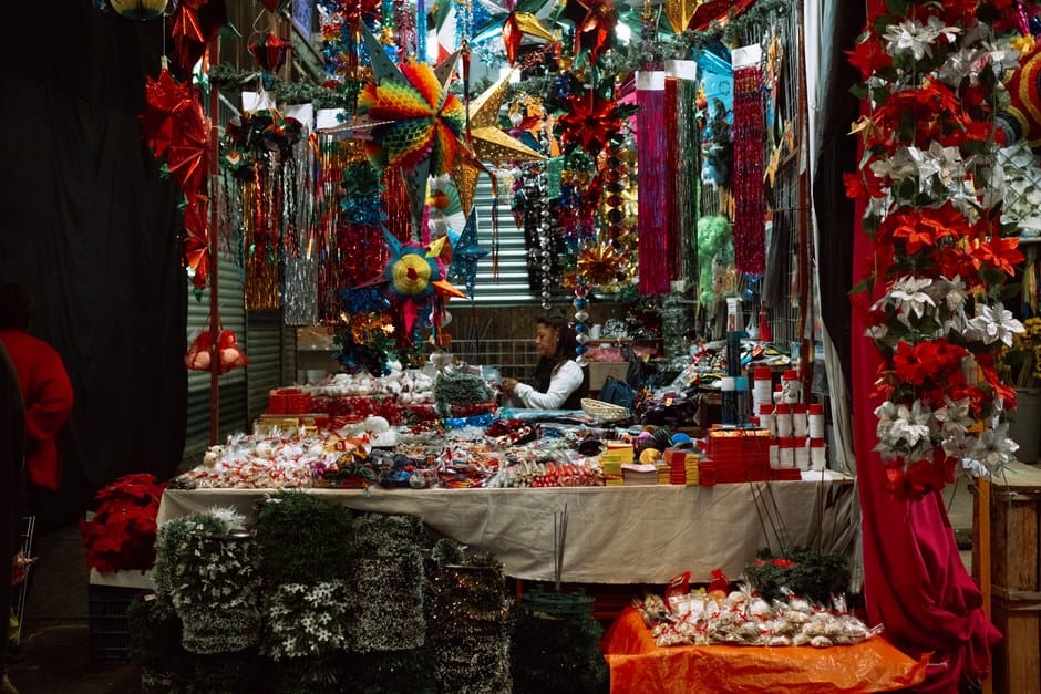 Decoraciones navideñas coloridas en un puesto de mercado en la Ciudad de México, CDMX, con luces y adornos festivos.