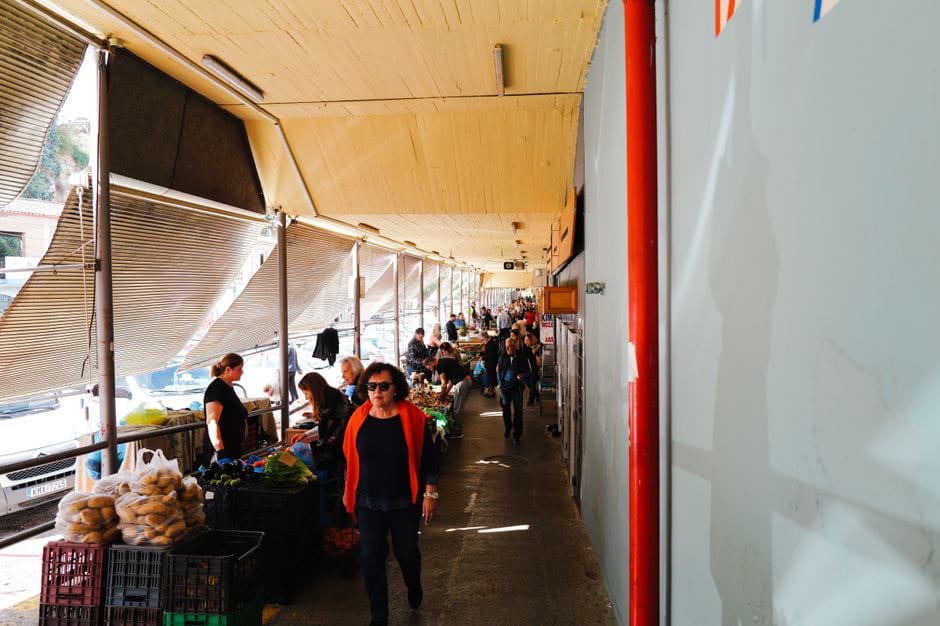 Un animado mercado interior lleno de gente que compra productos frescos.