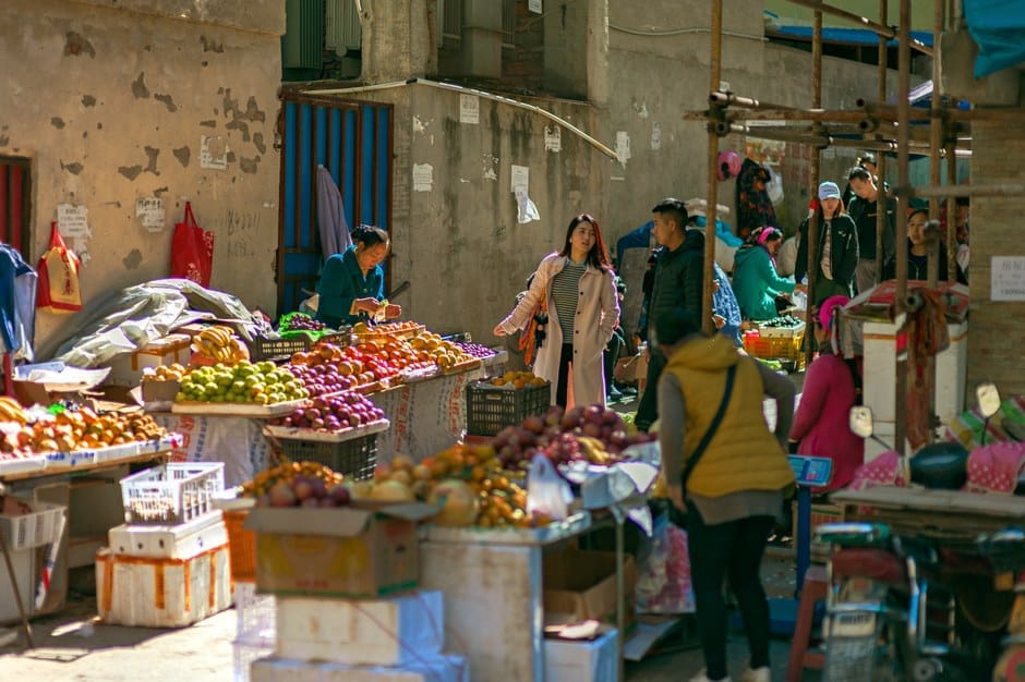 Un animado mercado al aire libre lleno de frutas y verduras coloridas y compradores diversos.