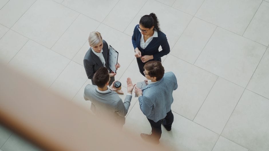 Toma aérea de un equipo empresarial diverso discutiendo un proyecto en el interior.