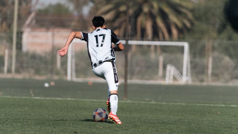 Un joven futbolista dribla el balón en un campo soleado vistiendo una camiseta con el número 17.