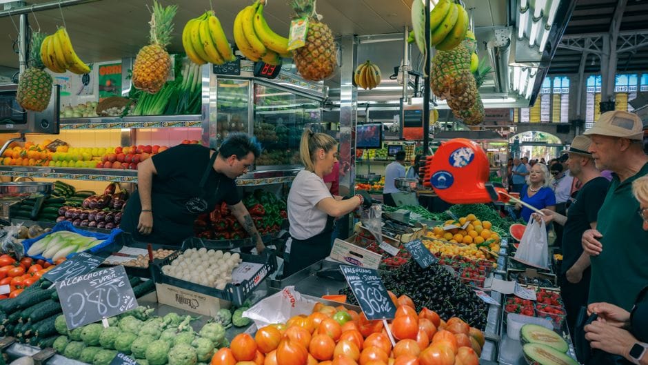 Concurrido mercado en Valencia con diversas frutas y verduras.
