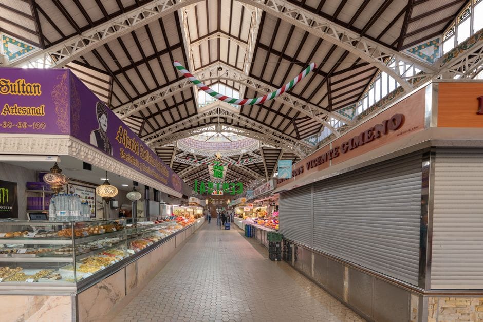 Vista interior del Mercado Central de Valencia mostrando su diseño arquitectónico y puestos de comida.