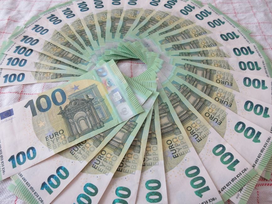 Primer plano de un abanico de billetes de 100 euros dispuestos en un artístico patrón circular sobre una superficie textil.