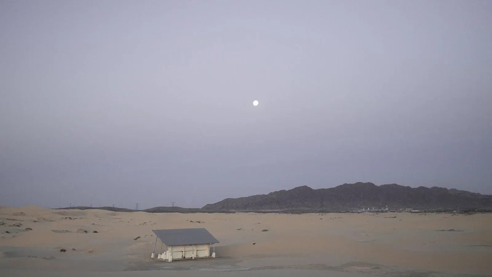 Serene view of an abandoned house in Samalayuca Desert under the early morning moonlight.
